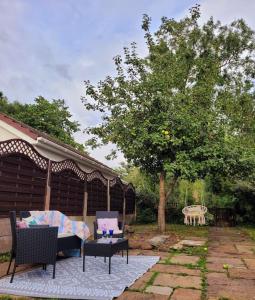 a patio with a couch and chairs and a tree at Riverside Bungalow - direct river access! in Ystradgynlais