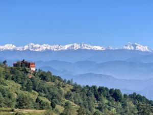 a house on a hill with snow capped mountains in the background at Hotel Sakura Durbar in Nagarkot