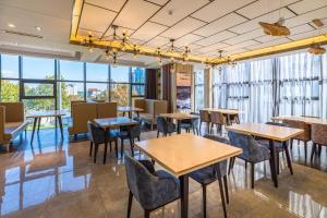 un restaurante con mesas, sillas y ventanas grandes en Atour Hotel Weihai City Center, en Weihai