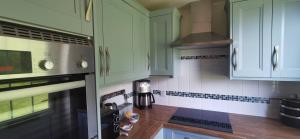 a kitchen with green cabinets and a counter top at The Wee Hoose in Dumfries