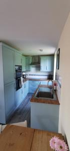 cocina con armarios azules, fregadero y mesa de madera en The Wee Hoose en Dumfries