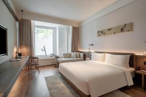 Schlafzimmer mit einem großen weißen Bett und einem Schreibtisch in der Unterkunft Sahe Hotel Shanghai World Expo in Shanghai
