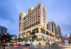 Atour X Hotel Hangzhou West Lake Wulin Plaza Yan'an Road في هانغتشو: مبنى كبير على شارع المدينة ليلا