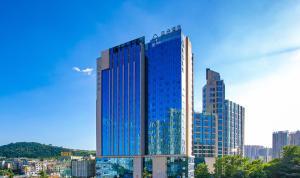 ein hohes Gebäude mit blauen Fenstern in einer Stadt in der Unterkunft Atour Hotel Guiyang Century City Shopping Center in Guiyang