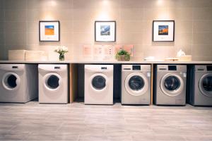 a laundry room with four washing machines and a counter at Atour Hotel (Turpan Wenhua West Road) in Turfan