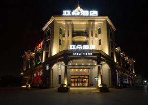 a building with a sign on top of it at night at Atour Hotel Shanghai Xinzhuang in Shanghai