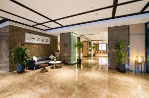 a lobby with a couch and potted plants at Atour Hotel Shenyang Hunnan Olympic Sports Center in Shenyang