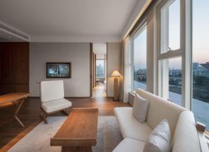 ein Wohnzimmer mit einem Sofa, einem Tisch und Fenstern in der Unterkunft Sahe Hotel Shanghai World Expo in Shanghai