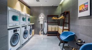 a laundry room with washing machines and a blue chair at Atour Light Hotel Shandong Road CBD Qingdao in Qingdao