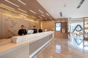 three men standing at a reception counter in a lobby at Atour Hotel Chengdu Wenshufang in Chengdu