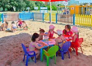 a group of children sitting at a table in the sand at Hotel Montecarlo in Bibione
