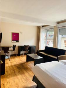 um quarto de hotel com uma cama, um sofá e uma mesa em Résidence Le Grand Tétras- SPA THERMAL INCLUS em Ax-les-Thermes