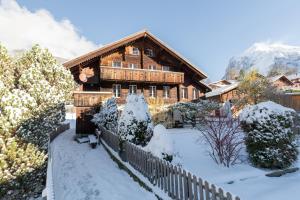 une maison en bois dans la neige avec une clôture dans l'établissement The Bergidyll Apartment - GRINDELHOMES, à Grindelwald