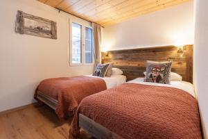 - 2 lits dans une chambre dotée de murs en bois et de parquet dans l'établissement The Bergidyll Apartment - GRINDELHOMES, à Grindelwald