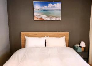 a bedroom with a bed and a picture of the beach at Haeundae Bona Travel in Busan