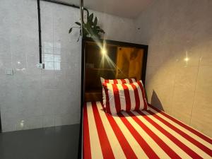 uma cama com riscas vermelhas e brancas num quarto em Por Chey Hostel em Battambang