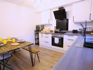 a kitchen with white cabinets and a table and a stove at Pass the Keys King Bed House Next To Heaton Park WM Discounts in Manchester