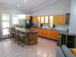 a kitchen with wooden cabinets and a island with bar stools at Shingalana Guest House in Hazyview