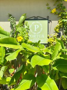 a sign for a restaurant with green leaves and flowers at Portuá Chalés in São Miguel dos Milagres