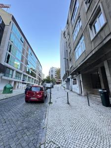 une voiture rouge garée dans une rue en briques avec des bâtiments dans l'établissement Central Lisbon by Trip2Portugal, à Lisbonne