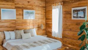 ein Schlafzimmer mit einem Bett in einem Zimmer mit Holzwänden in der Unterkunft Sangat Indah Wooden House Uluwatu in Uluwatu