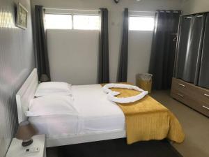 a bedroom with a white bed with a yellow blanket on it at Les Lauriers du Rocher 2 in Le Diamant