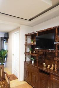 a living room with a television on a wooden entertainment center at Casa D' Hiyas Whole House Homestay in Panglao in Panglao