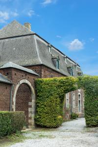 ein Backsteinhaus mit einer Hecke davor in der Unterkunft B&B La Ferme de l'Hosté in Wavre