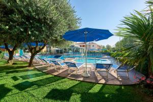 a group of chairs and an umbrella next to a pool at Junior Family Hotel in Cavallino-Treporti