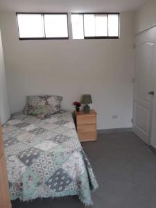 a bedroom with a bed with a comforter and two windows at Terraza más habitaciones en La Molina in Lima