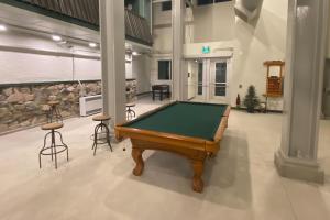 a pool table in a large room with stools at Snow Ghost Inn, Unit #311 in Big White