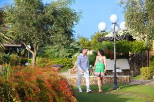 un hombre y una mujer de pie en un jardín en Hotel Baia Di Nora en Pula