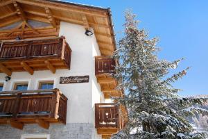 a snow covered christmas tree in front of a building at Al Bait da Marangona in Livigno