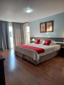 a bedroom with a large bed with red pillows at Athos Hotel in Teresópolis