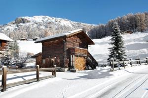 una cabaña de madera en la nieve con una valla en Al Bait da Marangona, en Livigno