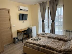 a bedroom with a bed and a desk and a television at ZaraApartHotel in Sofia