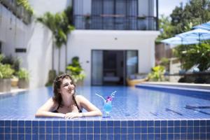 a girl with a drink in a swimming pool at Grand Yard La Residence in Siem Reap