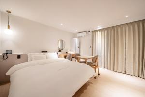 a white bedroom with a large bed and a table at HOTEL SOHA in Gumi