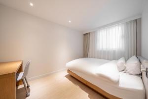 a bedroom with a bed and a desk and a window at HOTEL SOHA in Gumi