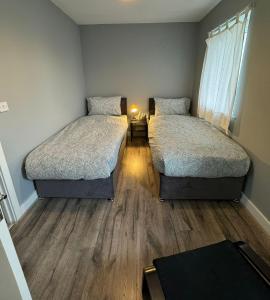 two beds in a small room with wooden floors at ane in Peterborough