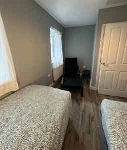 a bedroom with two beds and a chair next to a door at ane in Peterborough