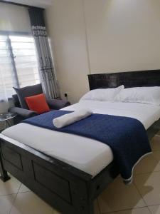 a bedroom with a large bed and a chair at B&S Studio apartment, Voi Town in Voi