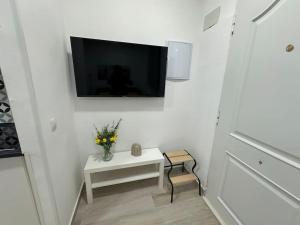 a white room with a tv and a table with flowers at Market Martinez De La Riva I in Madrid