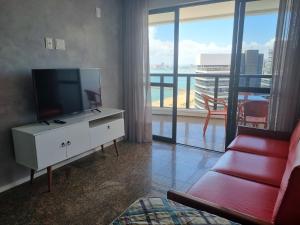 sala de estar con TV de pantalla plana y sofá rojo en Flats Mar Atlântico Residence, en Fortaleza