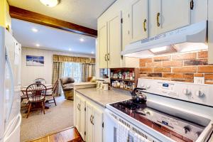 uma cozinha com armários brancos e um forno com placa de fogão em Poplar Stream Chalet em Carrabassett