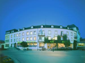 a large white building with a store in front of it at Hotel Kinnen in Berdorf