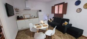 a kitchen and a living room with a table and chairs at Apartamentos Mirador en la Plaza de Zahara in Zahara de la Sierra
