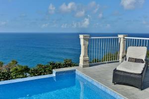 a chair sitting on a balcony overlooking the ocean at Cayman Villa - Contemporary 4 bedroom Villa with Stunning Ocean Views villa in Cap Estate