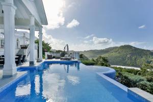 a swimming pool next to a house with a mountain at Cayman Villa - Contemporary 4 bedroom Villa with Stunning Ocean Views villa in Cap Estate