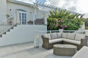 a patio with a couch and chairs on a balcony at Cayman Villa - Contemporary 4 bedroom Villa with Stunning Ocean Views villa in Cap Estate